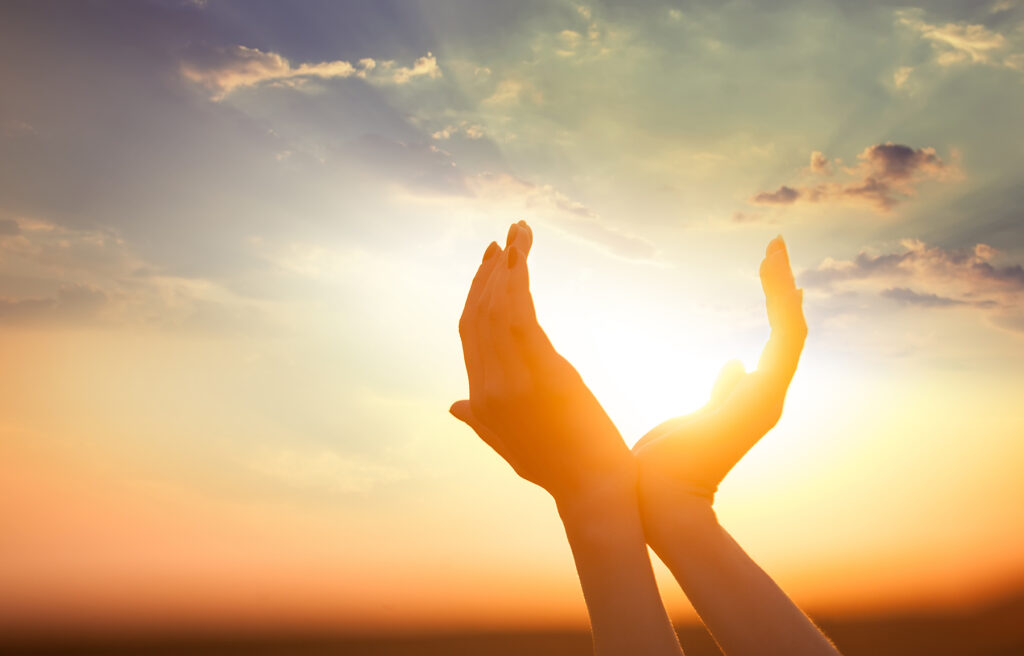 Handen reiken naar de opkomende zon